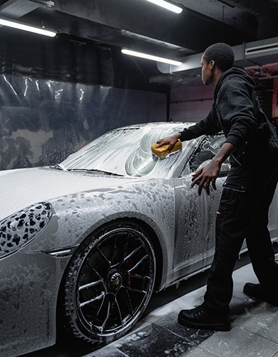 man washing a car with foam at car service