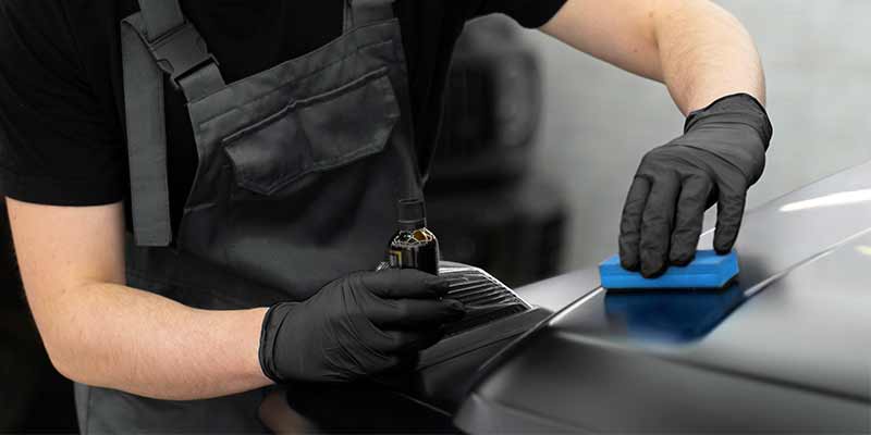 man doing a ceramic paint protection on black car