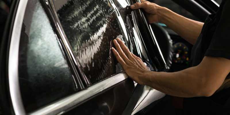 man tinting a black car window